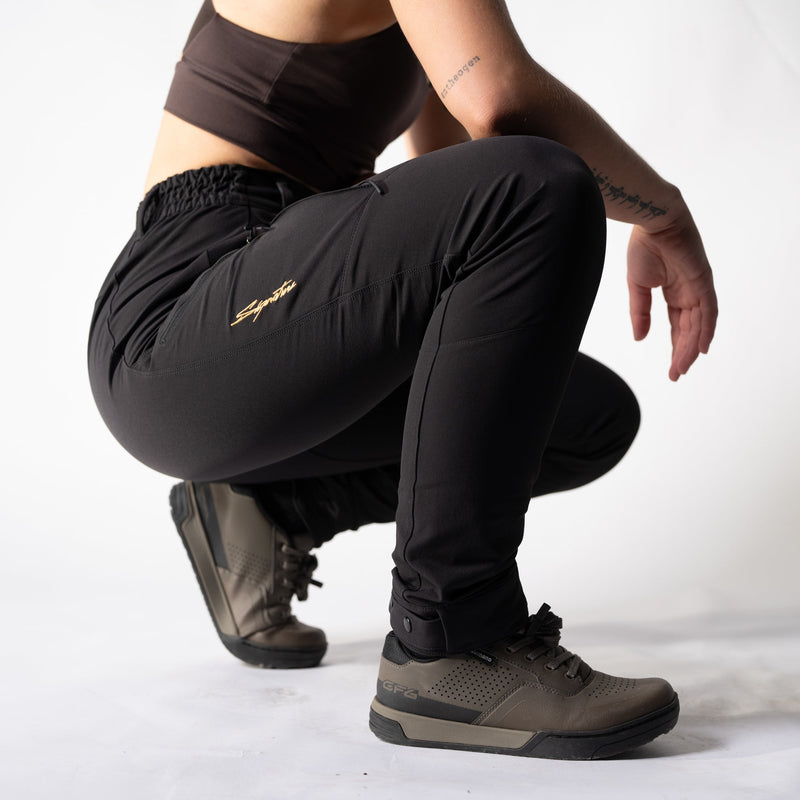 Person wearing black signature rover pants and brown shimano gf6 shoes on a white background