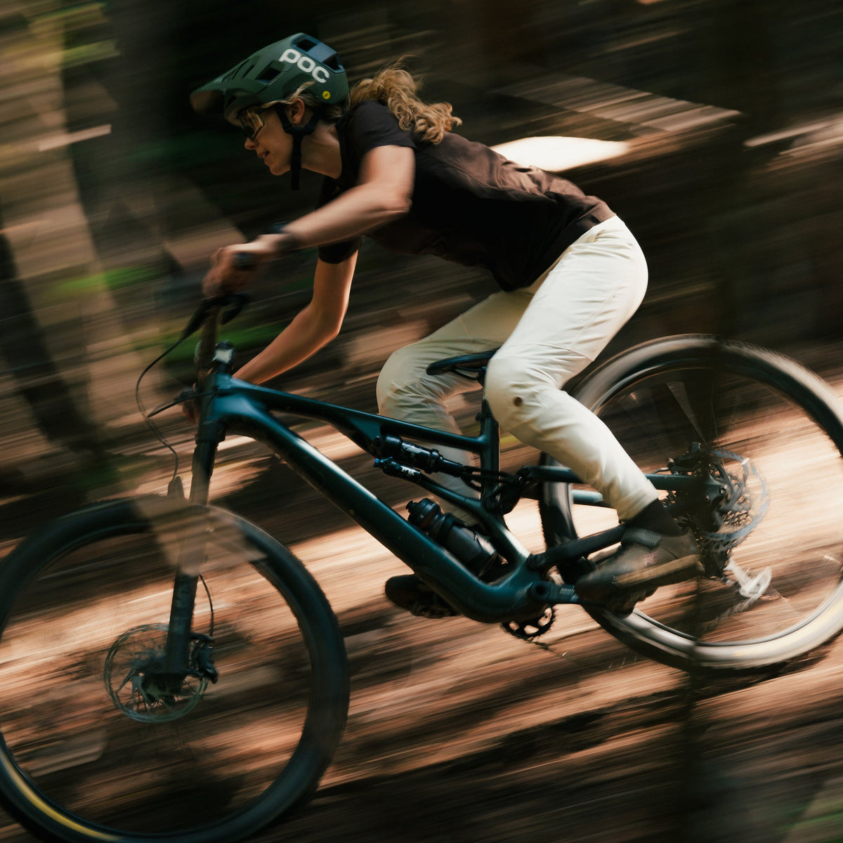 Elise Tomalty riding a specializd mountain bike through a forest wearing Signature Juna Pants and Jersey