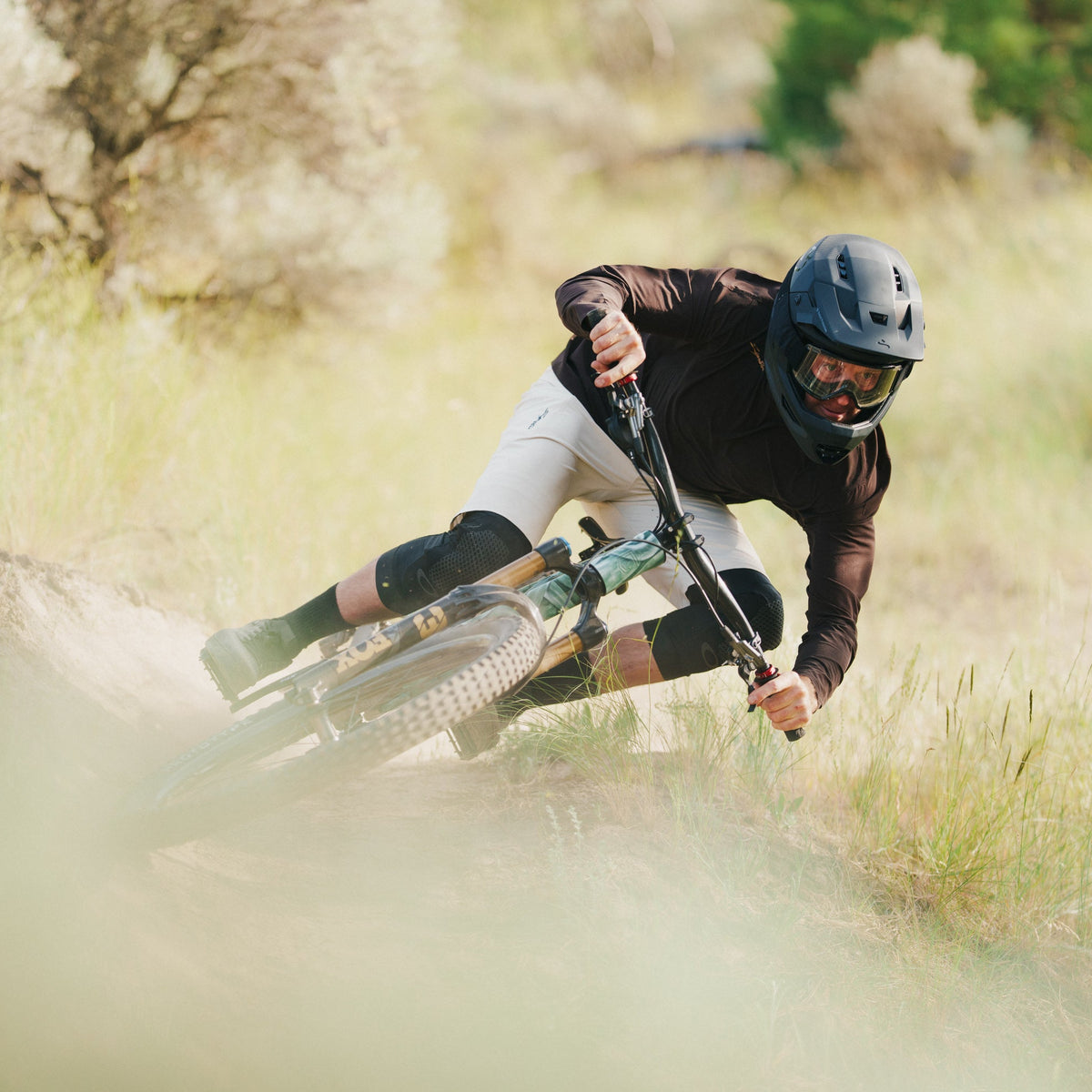 Person riding a mountain bike on a dirt trail with trees in the background