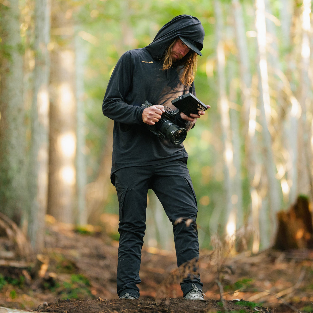 Person in a forest holding a camera and tablet