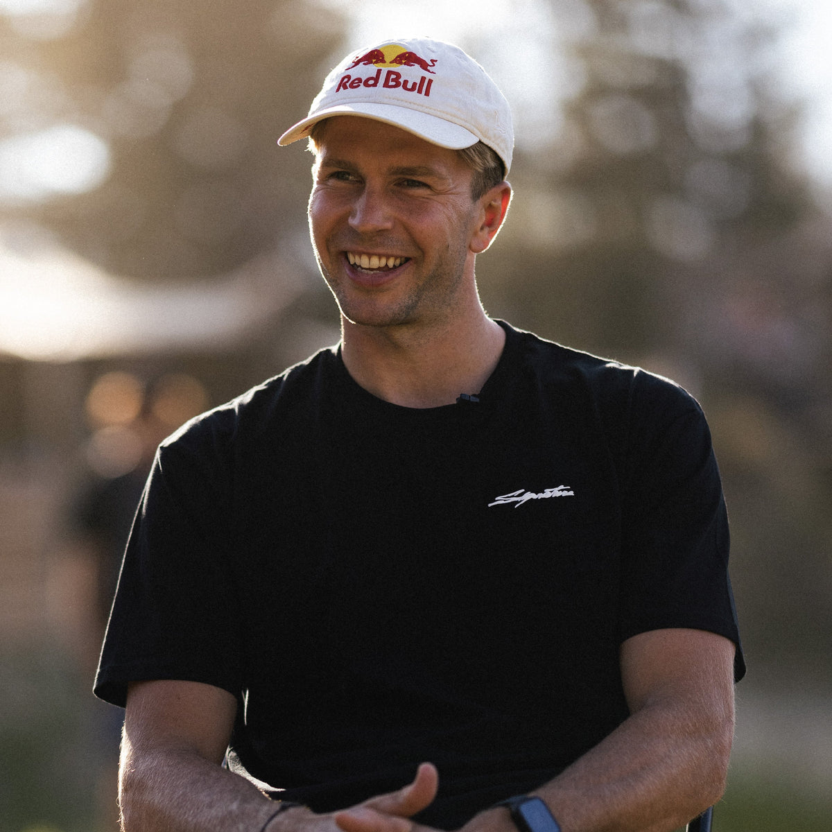 Dawid Godziek smiling wearing a red bull hat and signature short sleeve tee