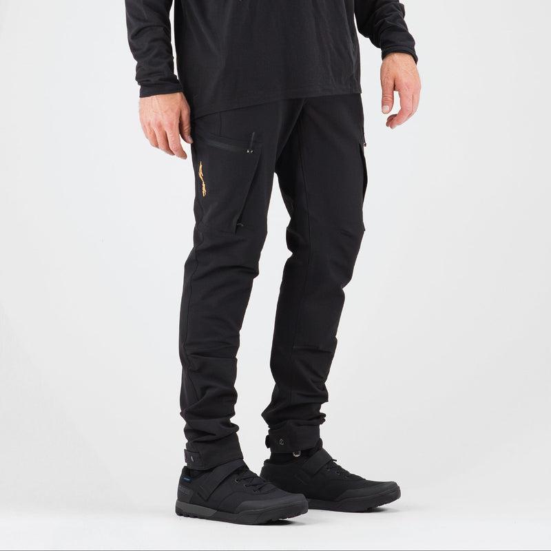 Person wearing a black hoodie and pants with a beige cap on a gray background